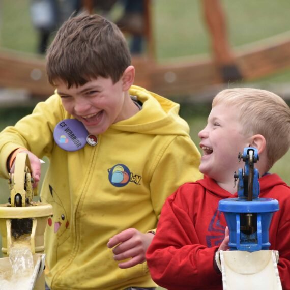 Two kids laughing while playing a water race game at an A ADVANCED CAREER PLANET PTYAgain adventure event.